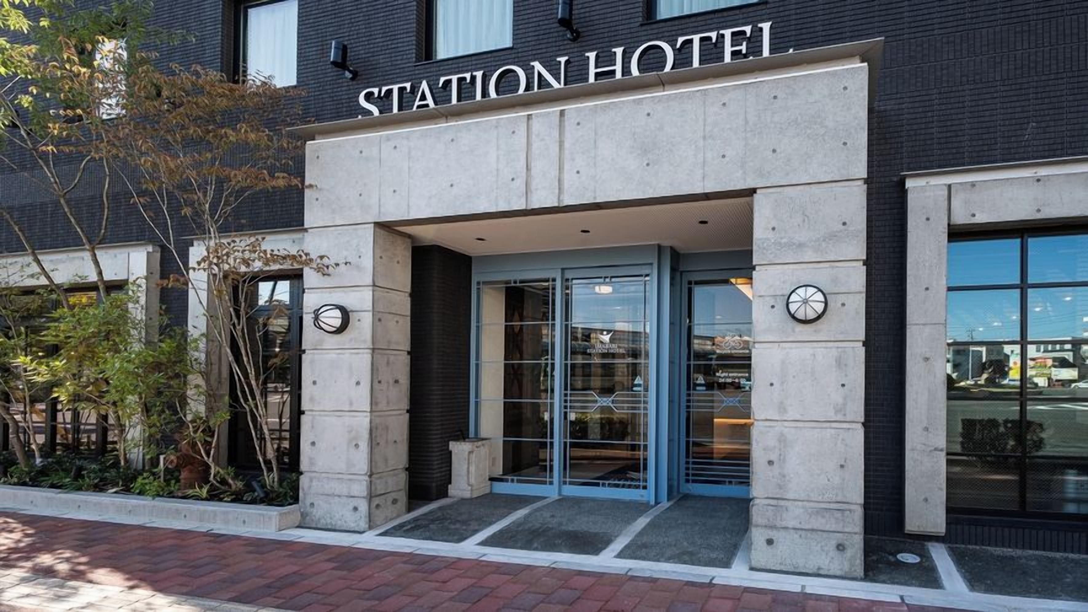 A hotel entrance with a sign reading 'STATION HOTEL,' a glass door, and a clock on the wall.