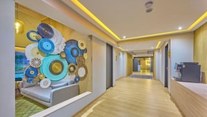 A modern hotel lobby with a wooden reception desk, a seating area with a sofa, and a decorative wall with circular patterns. - Hotel el Patio Cdmx (Mexico City)