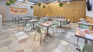 A spacious dining area with hexagonal patterned flooring, green chairs, and tables arranged for groups. - Hotel el Patio Cdmx (Mexico City)