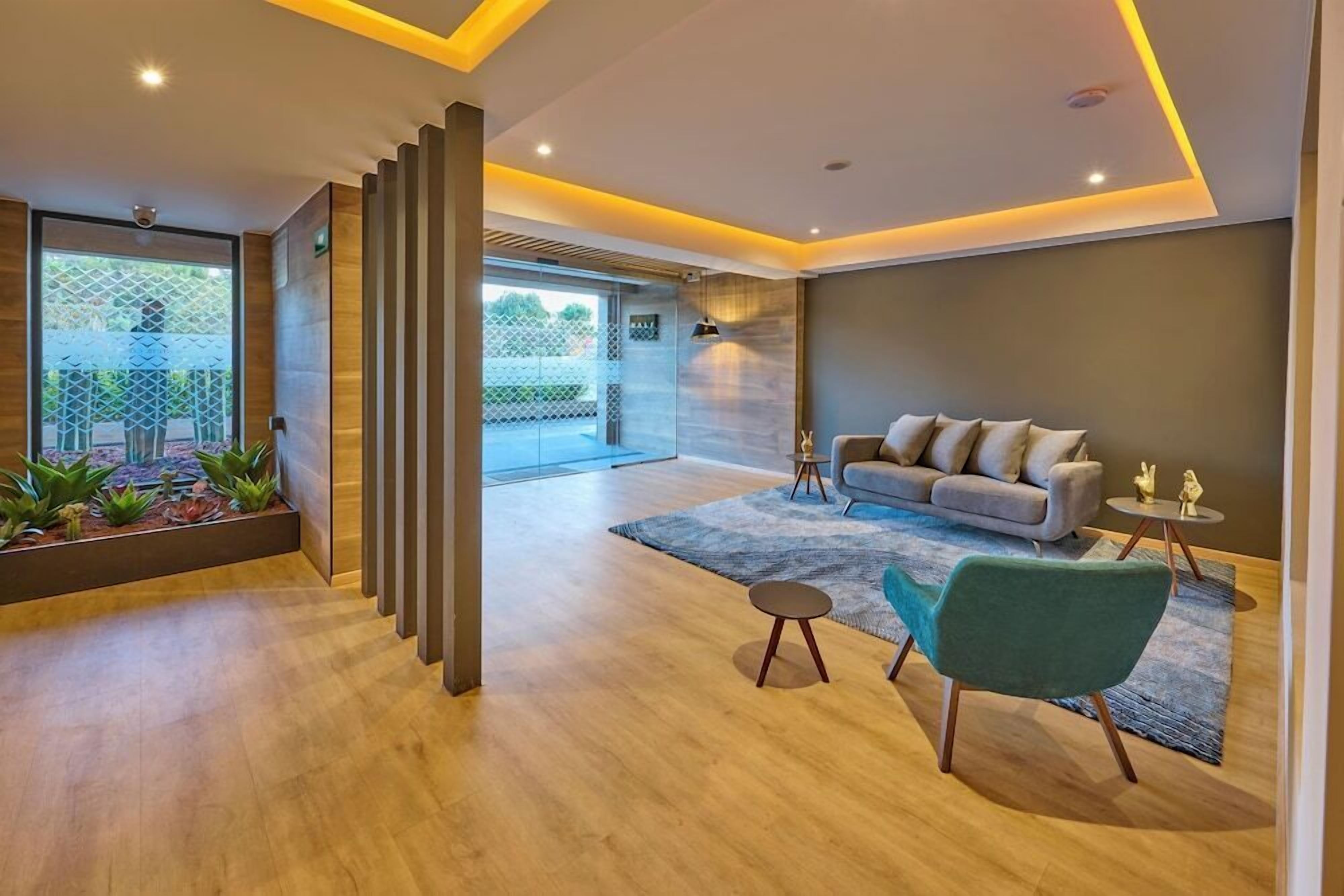 Una sala moderna con un sofá gris, un sillón azul turquesa y una pequeña mesa redonda.
