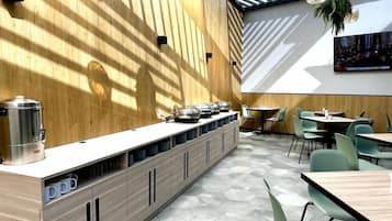 Un café moderno con una barra alargada, suelo de patrón hexagonal y sillas verdes.