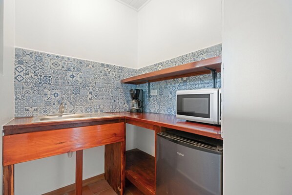 Una cocina compacta con encimera de madera, microondas blanco, cafetera y lavavajillas.