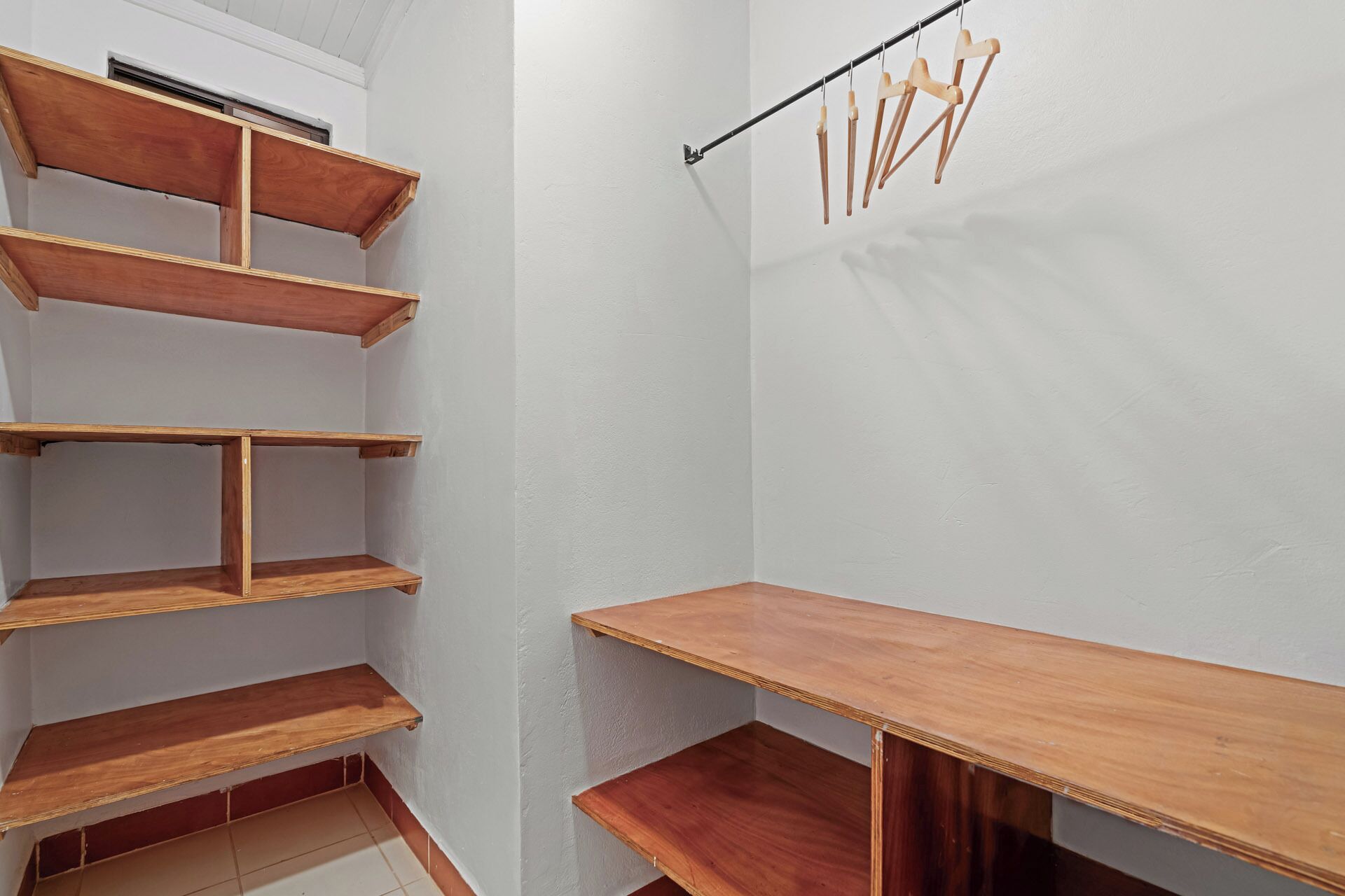 Una esquina de una habitación con estantes de madera y un tendedero.