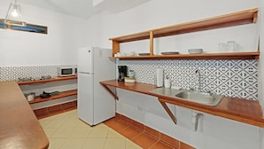 A modern kitchen with white cabinets, a built-in microwave, a refrigerator, wooden countertops, and patterned backsplash tiles.