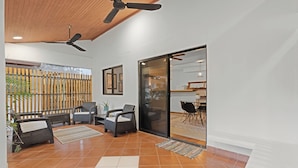 A modern interior with a ceiling fan, a sliding glass door leading to a dining area, and a wooden fence outside.