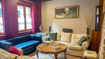 Un salon avec un canapé bleu, un canapé beige et une table basse en bois sur laquelle sont posés des livres.