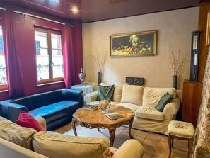 Un salón con un sofá azul, un sofá color beige y una mesa de centro de madera con libros.