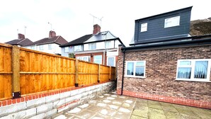 A residential property with a brick exterior, a wooden fence, and a paved courtyard. - Stylish Stay in Birmingham (Oldbury)