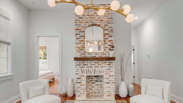 A modern living room with a brick fireplace, white sofas, and a glass coffee table. - The Saint's Suite - brand new 3 Bed/3 EnSuite Bath, 1 Block to King (Charleston)