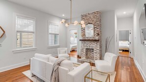 A modern living room with a fireplace, white sofas, and a chandelier. - The Saint's Suite - brand new 3 Bed/3 EnSuite Bath, 1 Block to King (Charleston)