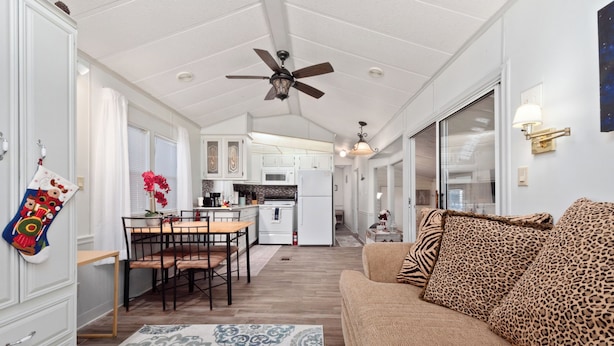 A spacious living area with a sofa, a dining table, and a kitchen in the background.