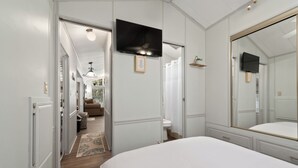 A bedroom with a large bed, a TV mounted on the wall, and a mirror.