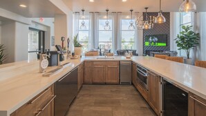 A modern kitchen with wooden cabinets, stainless steel appliances, and pendant lighting.