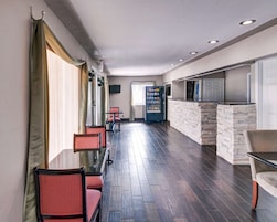 Un vestíbulo de hotel con una recepción, zona de estar y máquina expendedora.