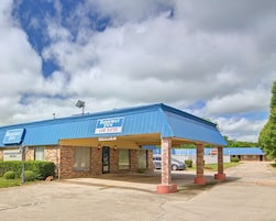 Un motel de una sola planta con techo azul y zona de estacionamiento techada.