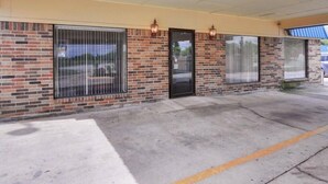 A building with a brick facade, large windows, and a covered entrance area. - Rodeway Inn Gainesville I-35 (Gainesville)