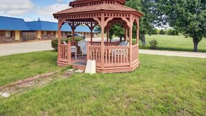 A gazebo with a wooden structure and a roof, surrounded by a grassy area and trees. - Rodeway Inn Gainesville I-35 (Gainesville)