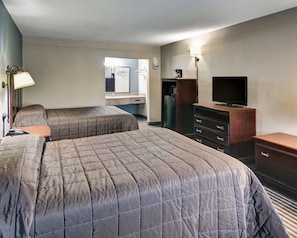 A hotel room with two beds, a dresser, a television, a mirror, and a coffee maker. - Rodeway Inn Gainesville I-35 (Gainesville)