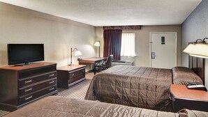 A hotel room with two beds, a desk, a TV, a dresser, and a window with curtains. - Rodeway Inn Gainesville I-35 (Gainesville)