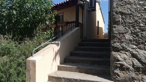A stone staircase leading to a building with a tiled roof and a window with a white frame. - Unique, comfortable apartment with beautiful view, quiet location. (Ansignan)
