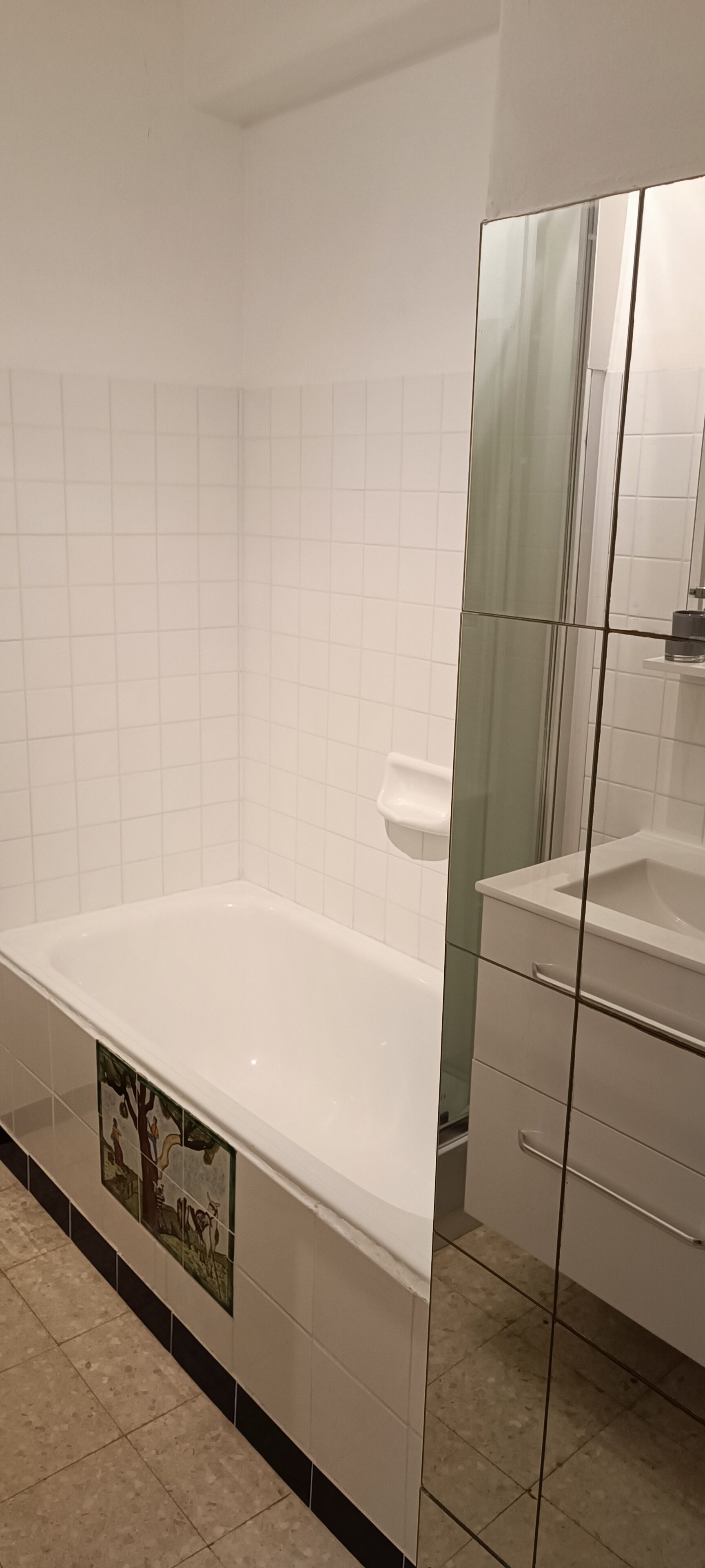 A bathroom with a white bathtub, a glass shower enclosure, and a tiled floor.