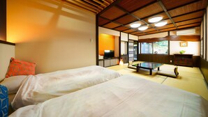 A traditional Japanese-style room with tatami flooring, two beds, a television, and a view of the outdoors. - Ureshino Onsen Kujaku (Ureshino)