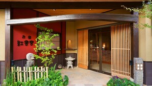 A traditional Japanese building with a curved wooden entrance, a stone lantern, and a small pagoda-style structure. - Ureshino Onsen Kujaku (Ureshino)