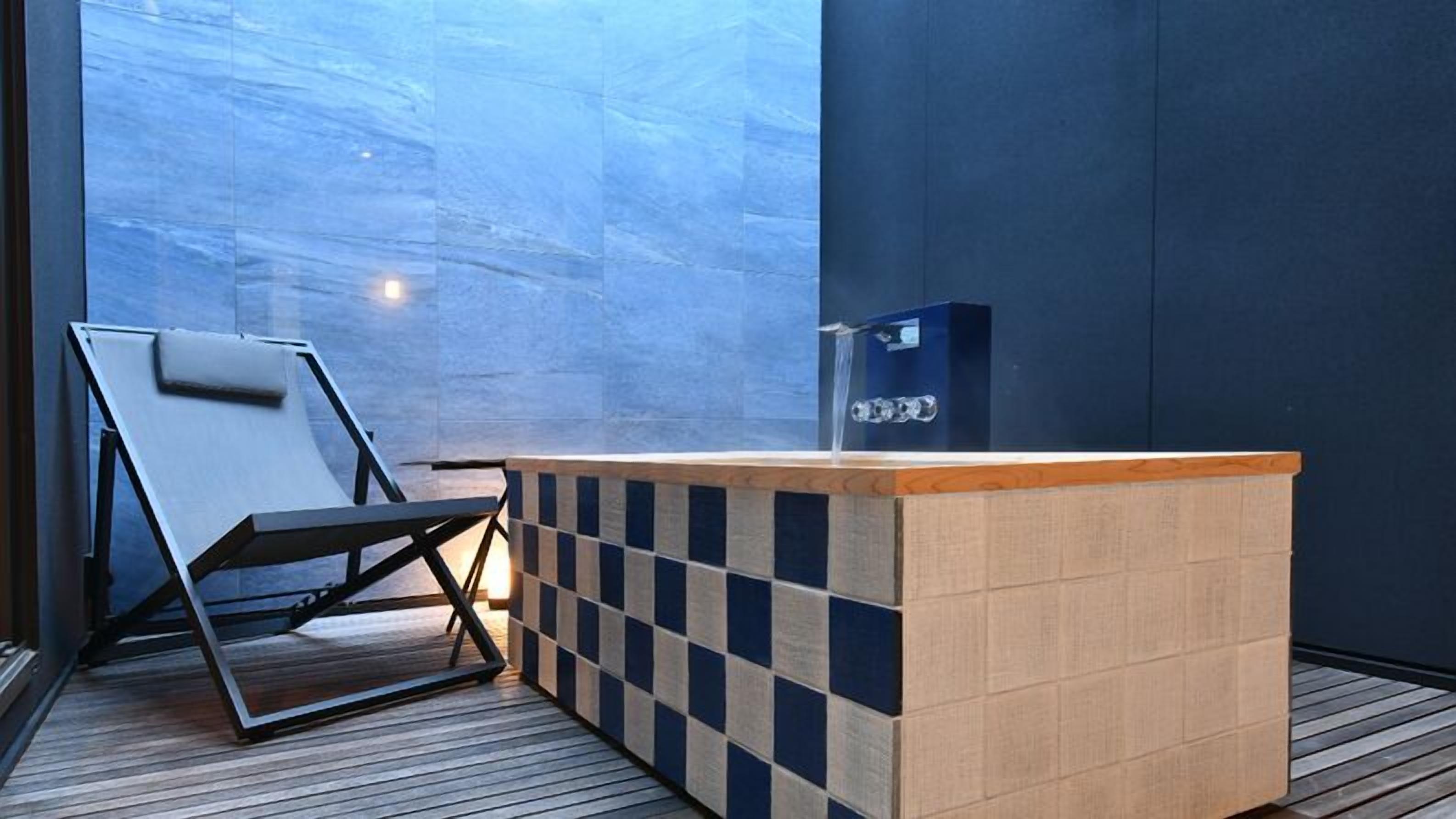 A modern bathroom with a checkered tile wall, a wooden bench, and a shower area.