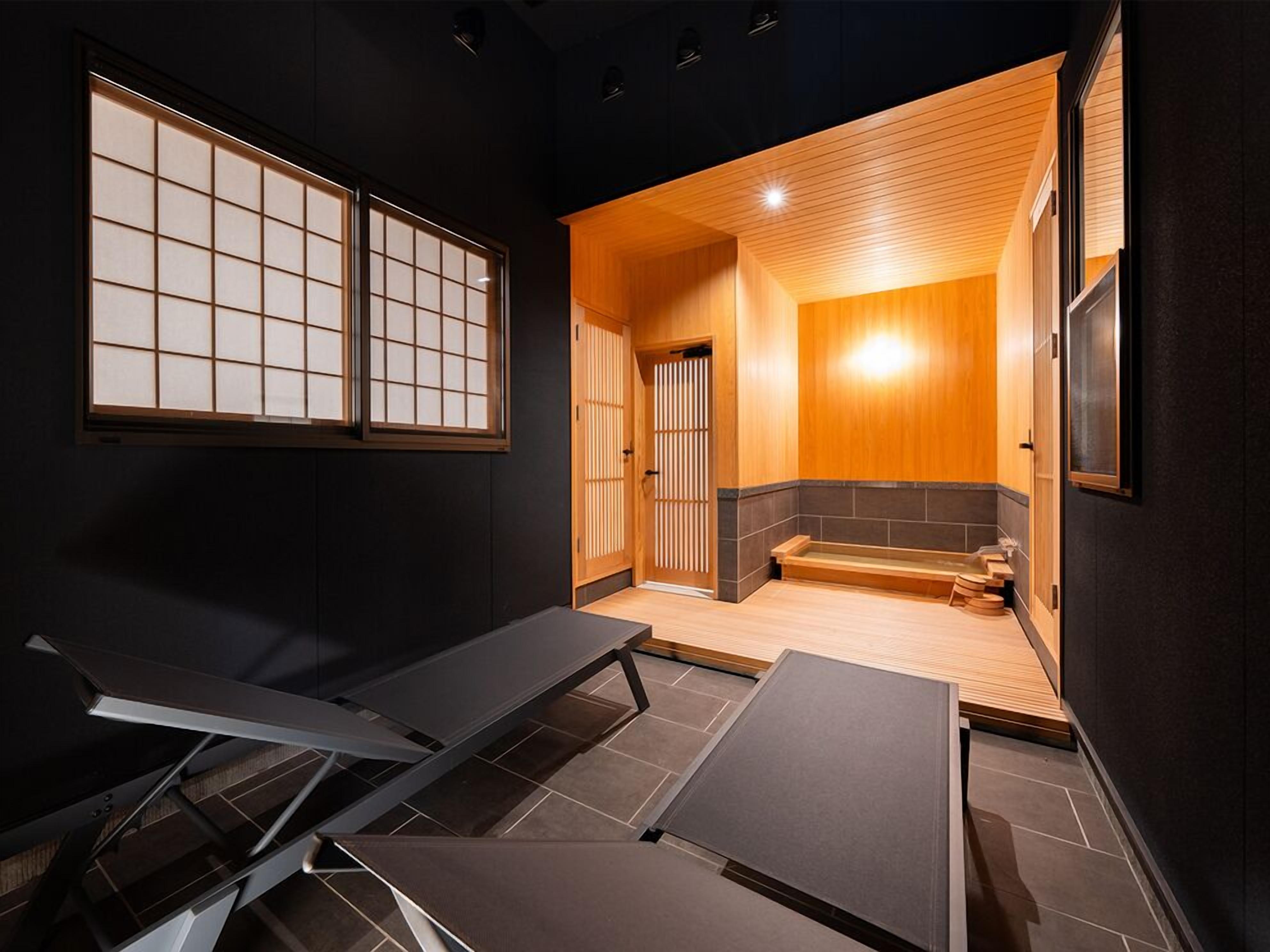 A traditional Japanese-style room with tatami flooring, a wooden bench, sliding doors, and a low ceiling.