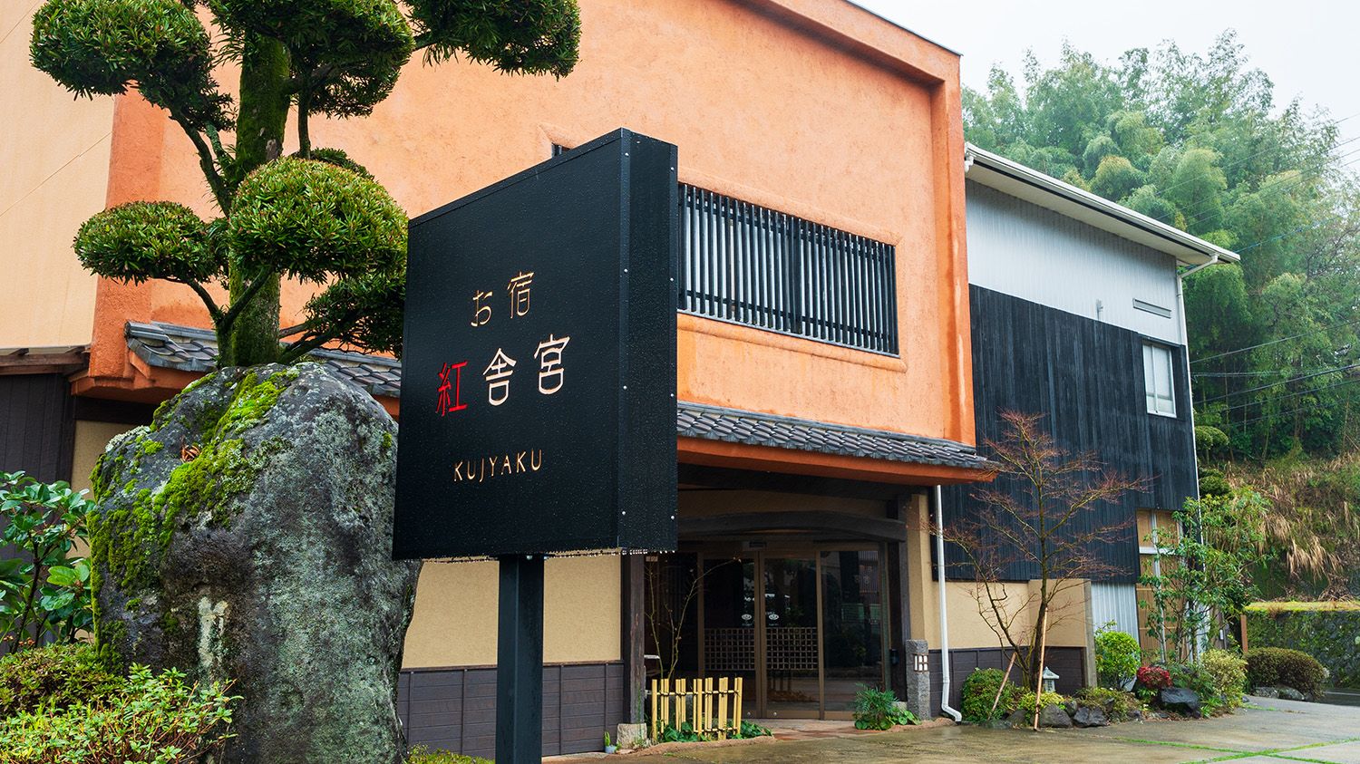 A building with a black signboard, a traditional entrance, and a modern upper section.