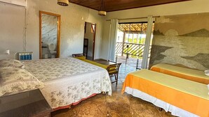 Een kamer met een bed, twee nachtkastjes, een stoel en een groot raam met uitzicht op het omliggende landschap.