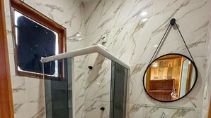 Een badkamer met een douchecabine van glas, een toilet, een wastafel met een marmeren blad en een spiegel aan de muur.
