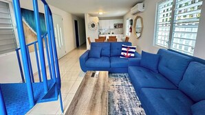 Una sala de estar con un sofá azul, una mesa de centro y una escalera azul.