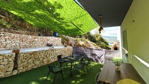 A patio with a stone wall, a table with chairs, and a hanging light fixture. - New, close to the beach apartment with parking (Mastrinka)