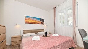 A bedroom with a bed, a nightstand, a wall-mounted painting, and a window with curtains. - New, close to the beach apartment with parking (Mastrinka)