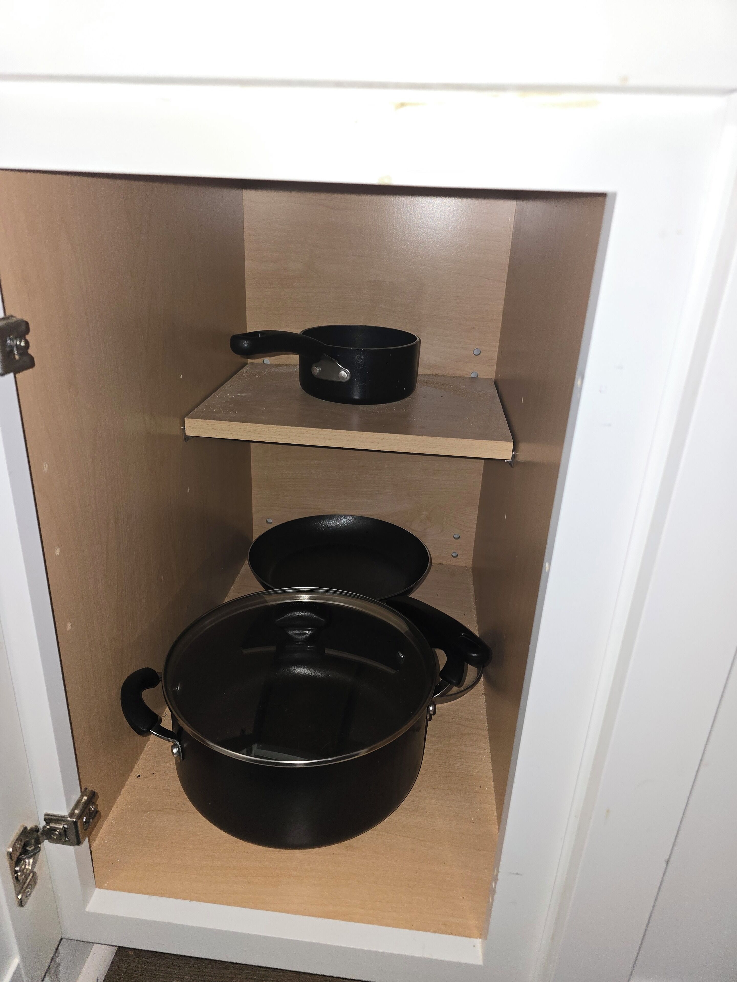Un meuble de cuisine contenant deux casseroles noires et une poêle.