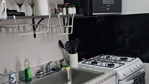 A kitchen with white cabinets, a black microwave, a gas stove, and a stainless steel sink. - Tranquil corporate Rental in lovely Minneapolis with WiFi (Minneapolis)