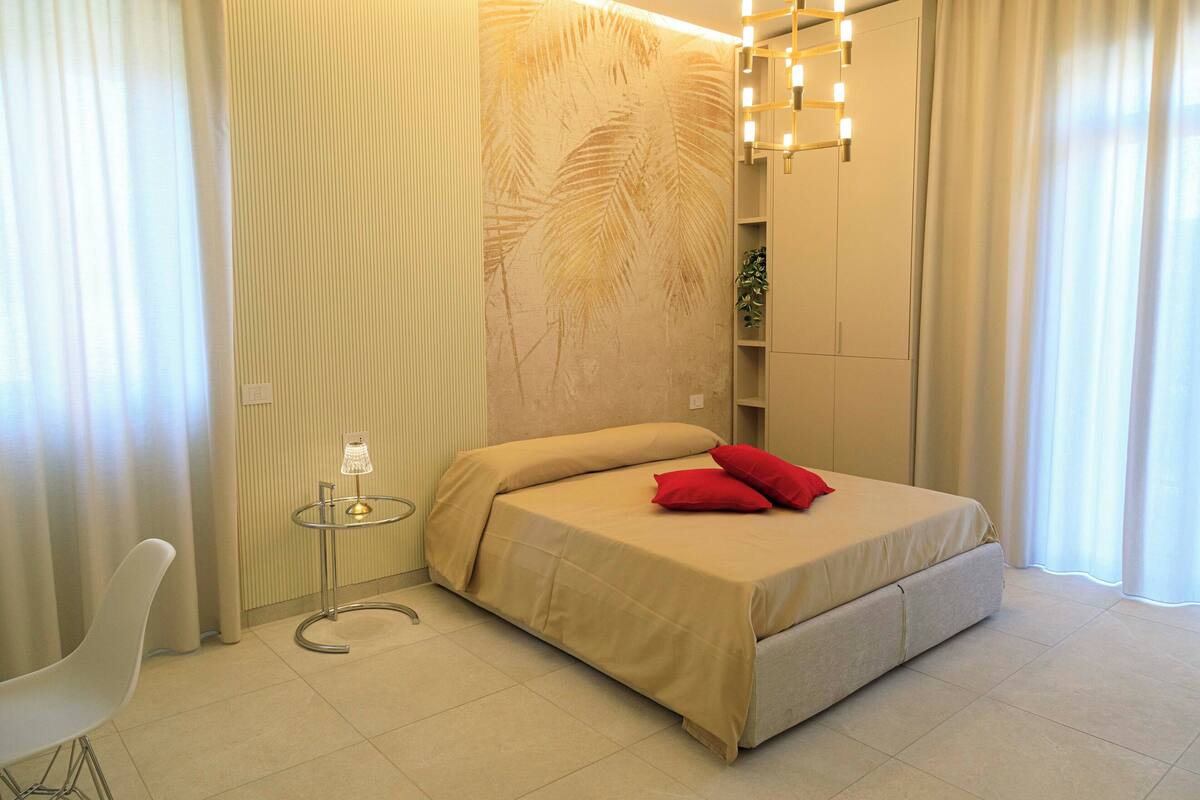 A modern bedroom with a bed, a small table, and a chair.