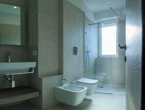 Une salle de bain moderne équipée d’une douche, de toilettes, d’un bidet et d’un lavabo.