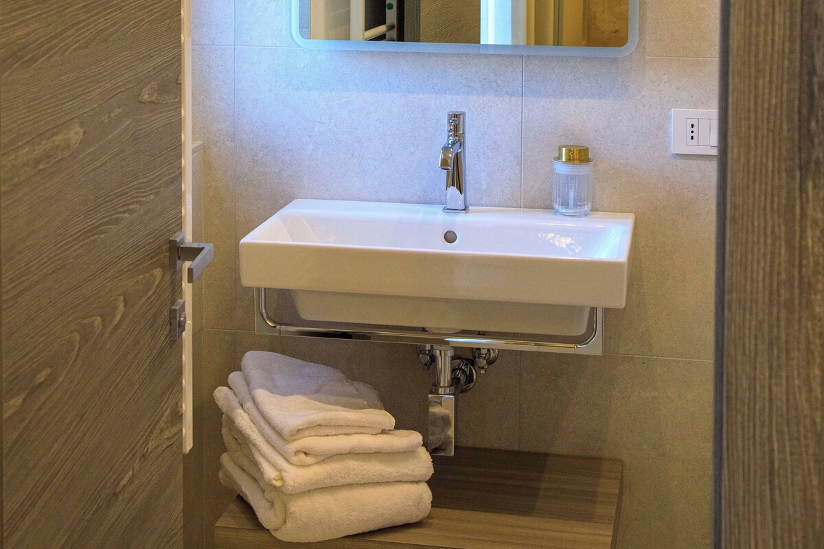 A modern bathroom with a white sink, a mirror, and a towel rack.