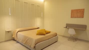 Un dormitorio con cama, mesitas de noche, un escritorio y una silla.
