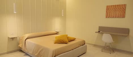 A bedroom with a bed, bedside tables, a desk, and a chair.