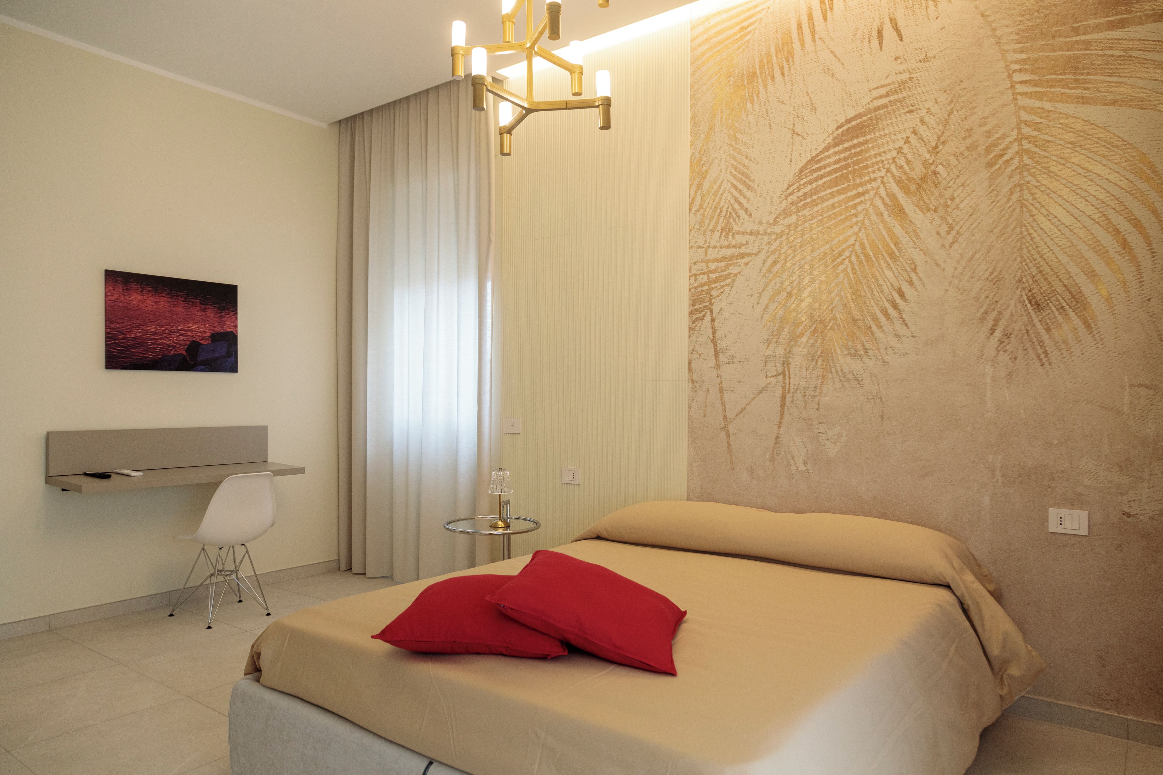 Una habitación de hotel moderna con cama, escritorio, silla y un ventanal con cortinas.