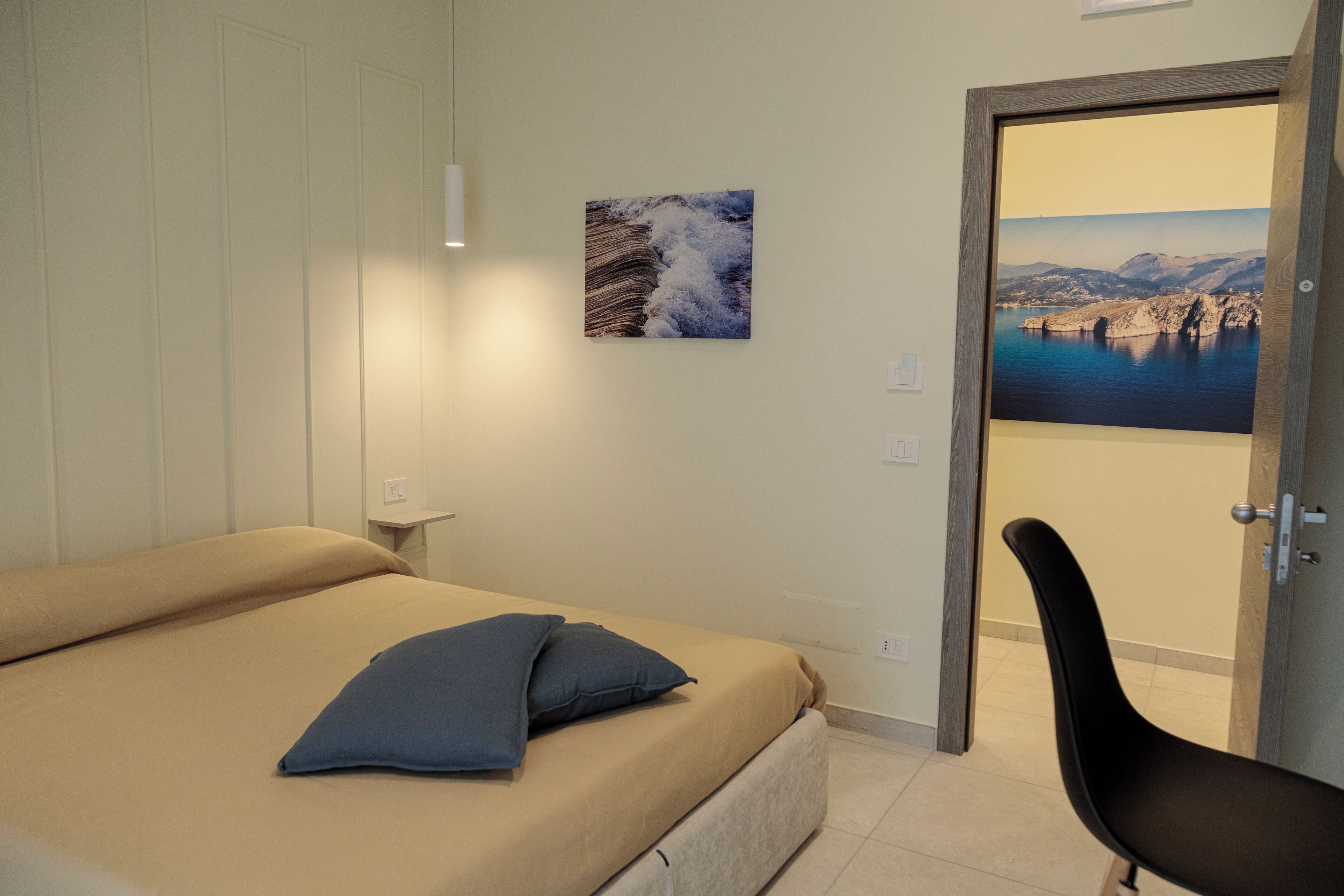 A bedroom with a bed, a chair, and two framed pictures on the wall.