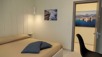 A bedroom with a bed, a chair, and two framed pictures on the wall.