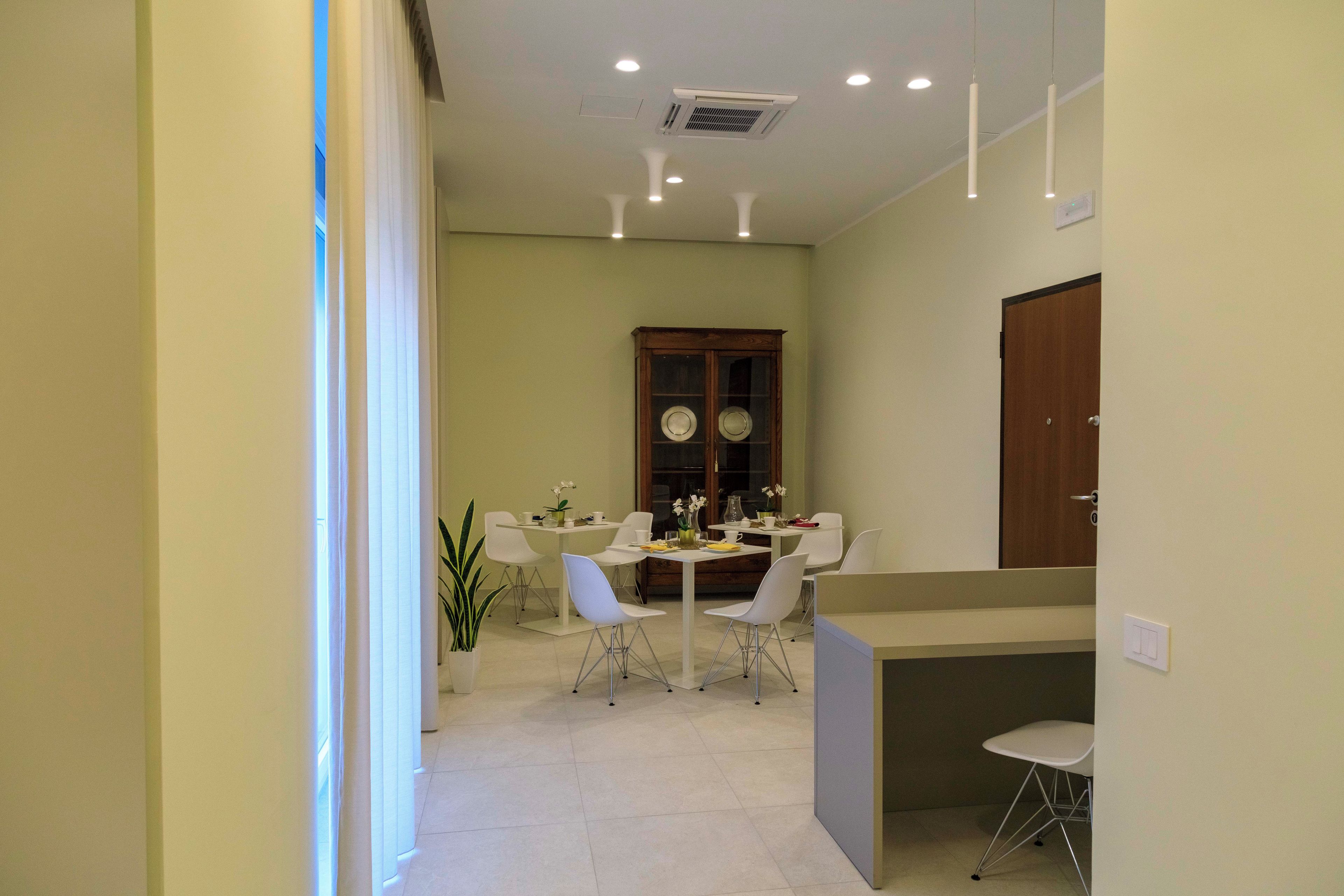 A dining area with a table and chairs, a cabinet with decorative plates, and a potted plant.