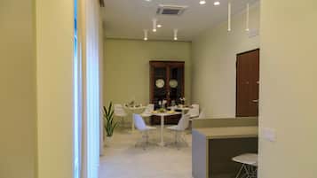 A dining area with a table and chairs, a cabinet with decorative plates, and a potted plant.