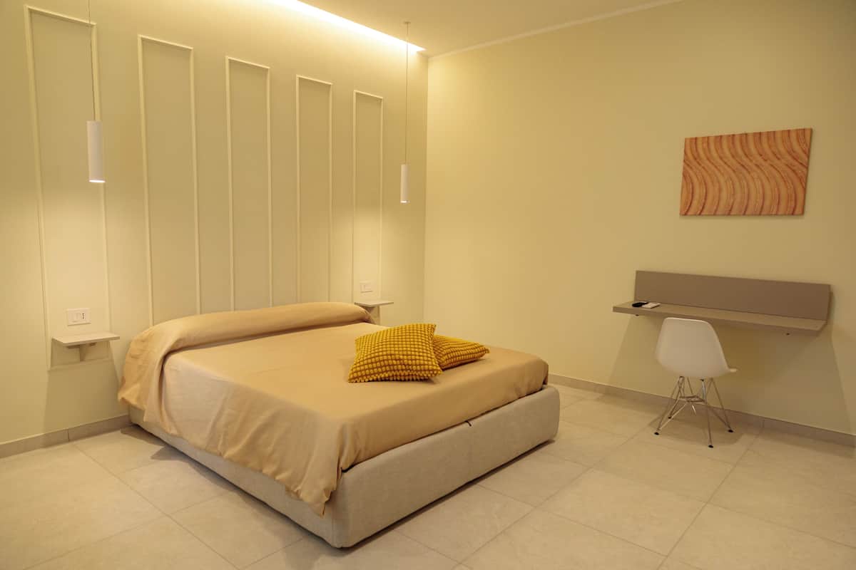 A bedroom with a bed, bedside tables, a desk, and a chair.