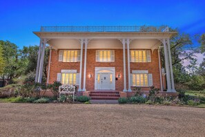 A two-story brick house with a covered porch, white columns, and a front door with a small porch.