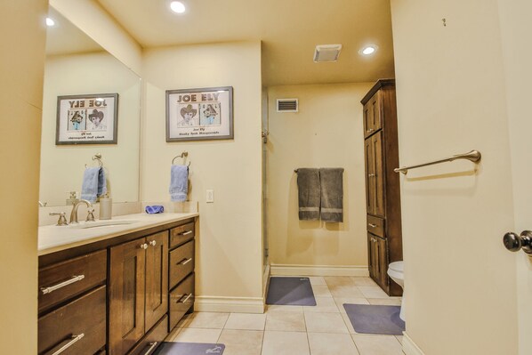 A bathroom with wooden cabinets, a sink, a mirror, and two framed posters on the wall.